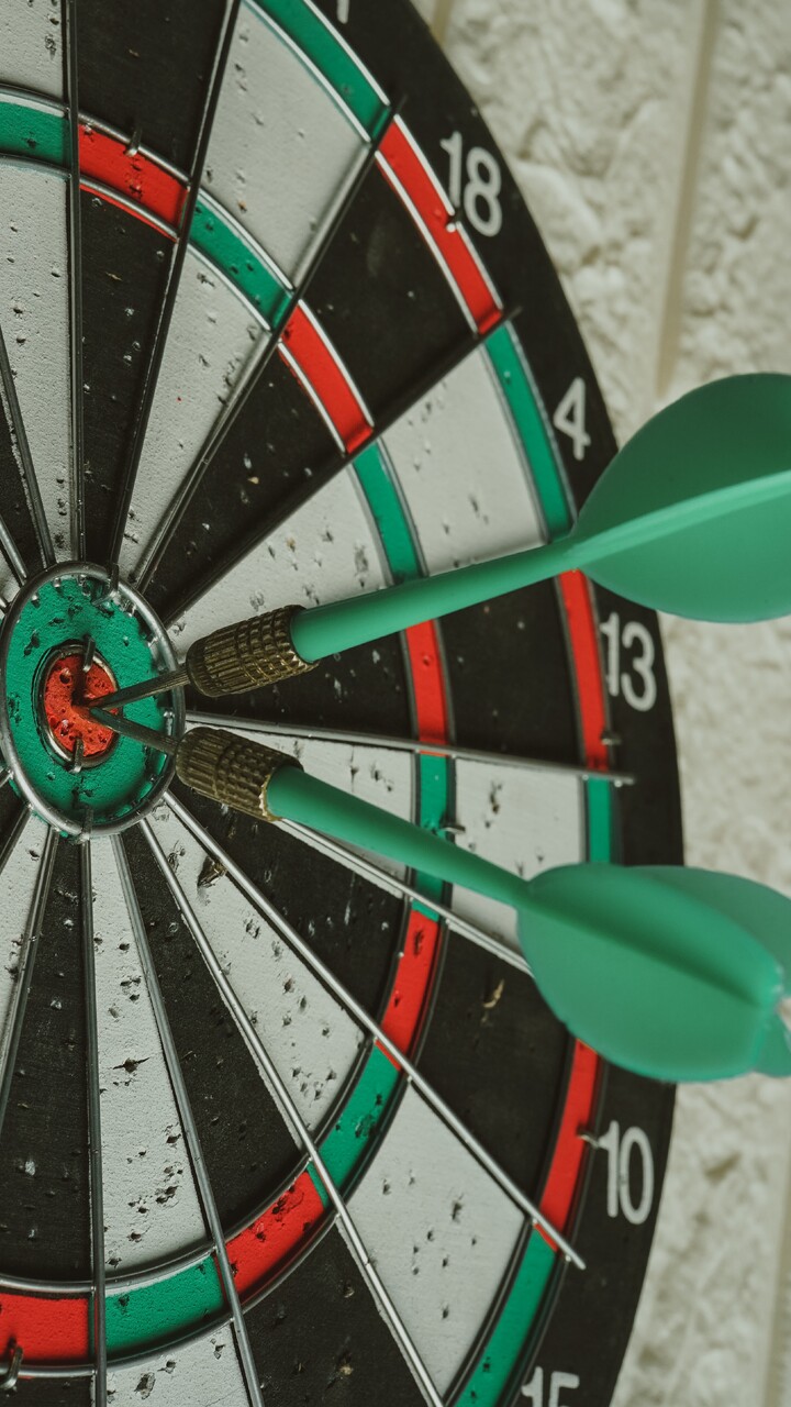 Darts Zielscheibe in rot, grün, schwarz und weiß mit zwei Pfeilen in der Mitte.